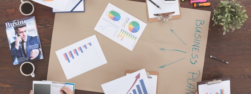 Top view of people sitting beside table, preparing business plan